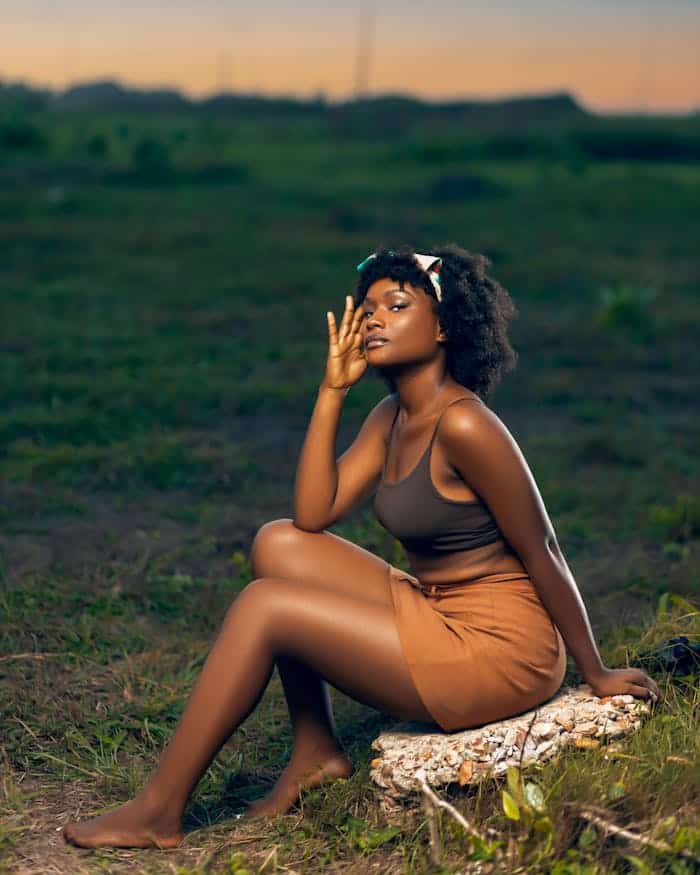 Elegant portrait of an African woman sitting outdoors, exuding confidence and grace at twilight.